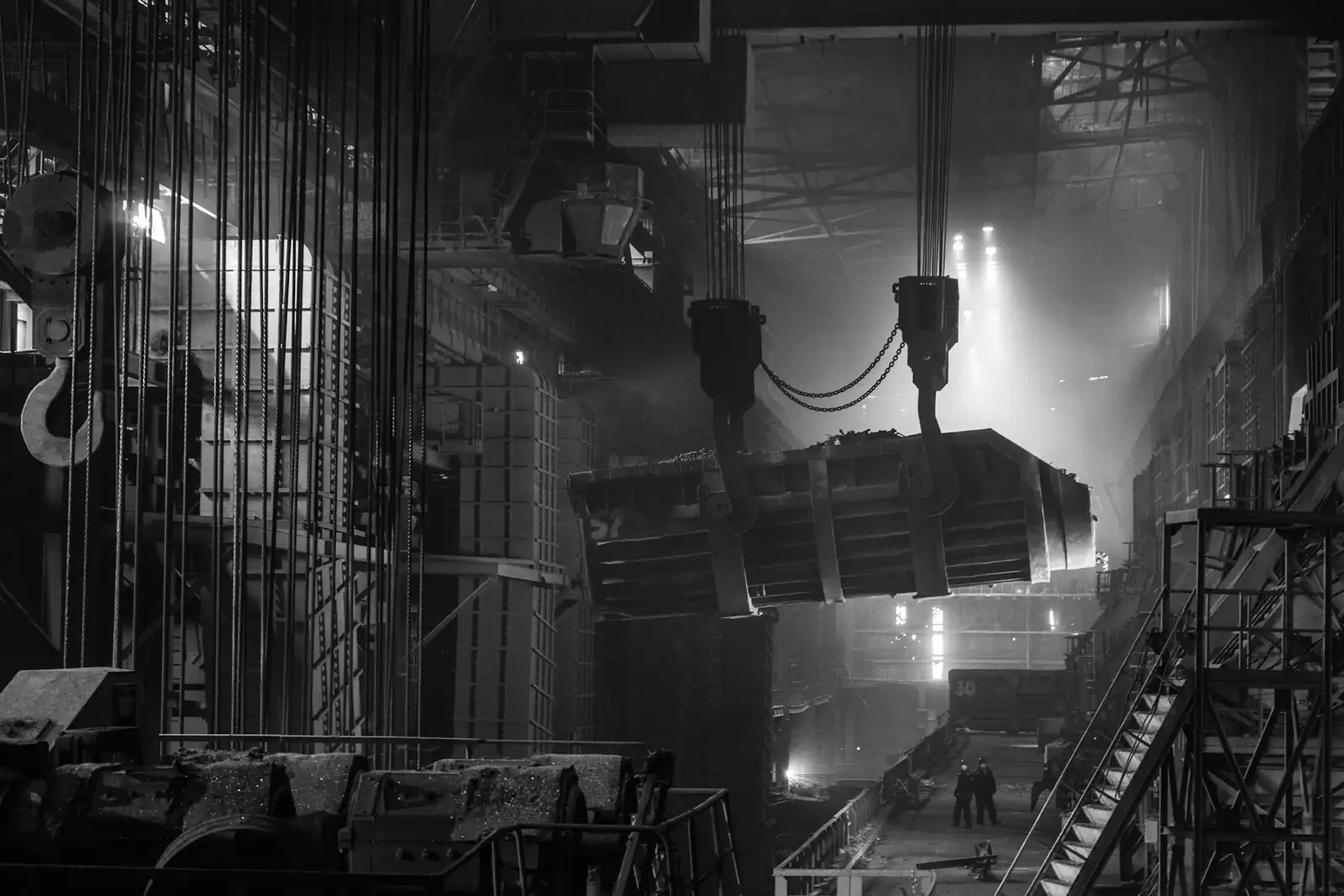 A ladle of molten steel lifted by a crane in a steel mill